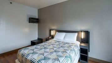 A bedroom with a bed, bedside tables, a wall-mounted TV, and a patterned bedspread.