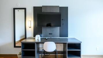 A modern hotel room with a desk, chair, and a large mirror.