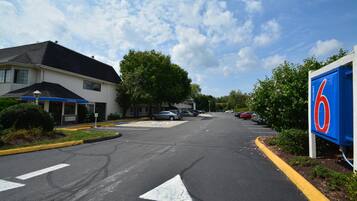 Un motel avec une enseigne bleue, un parking et un bâtiment sur lequel on peut lire « Bienvenue ».