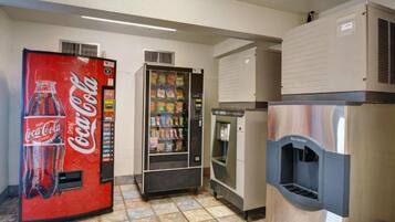 Et område med salgsautomater, inklusive en Coca-Cola dispenser, en automater med snacks og en vanddispenser.