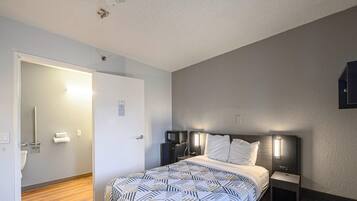 Een hotelkamer met een bed, nachtkastjes, een bureau, een magnetron en een toilet.