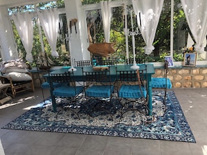 Eine Terrasse im Freien mit Tisch und Stühlen, einem gemusterten Teppich und einer Steinwand.