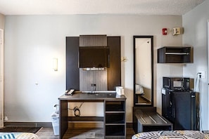 A compact hotel room with a kitchenette, a desk with a telephone, a mirror, and a microwave. - 2 Full Beds | Micfridge | Smoking (Wethersfield)