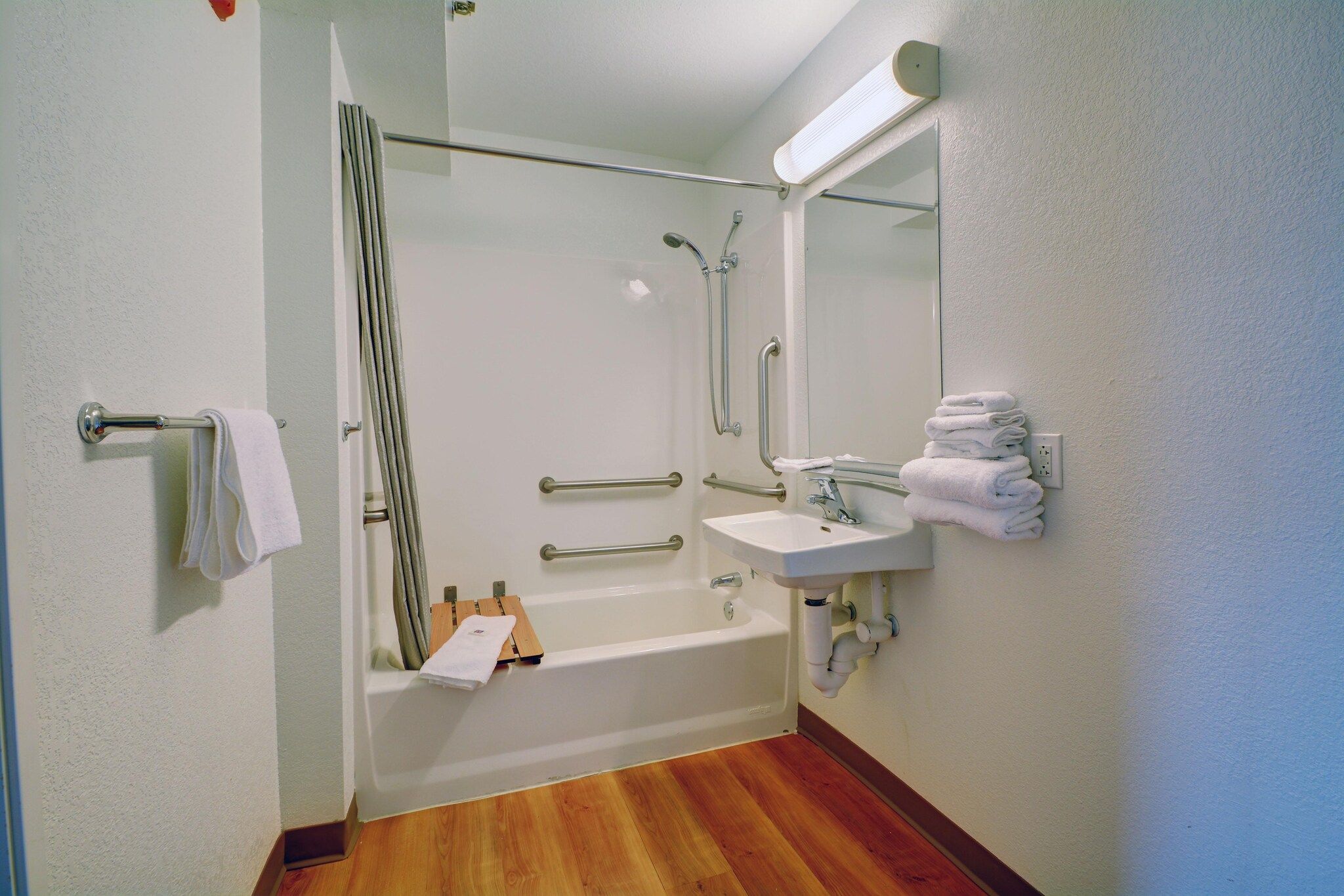 Een badkamer met een bad, een wastafel, een spiegel en een handdoekhouder.