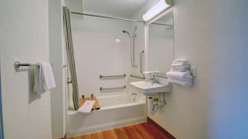Een badkamer met een bad, een wastafel, een spiegel en een handdoekhouder.