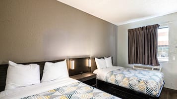 Una habitación de hotel con dos camas, un ventanal con cortinas y un calentador fijado a la pared.