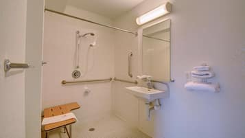 Een toilet dat toegankelijk is voor rolstoelen, met een douche, wastafel en een zitje.