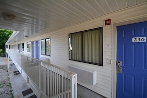 A row of motel rooms with individual doors, each marked with a number.