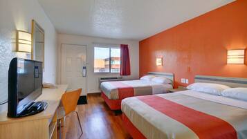 Habitación de hotel con dos camas, un escritorio con televisor y una ventana con cortinas.