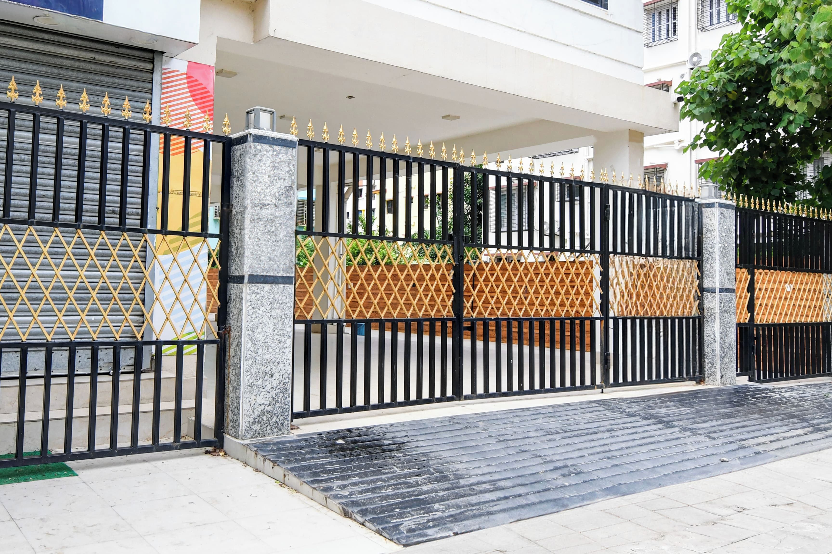 A gated entrance with a marble pillar, a metal gate with decorative spikes, and a wooden fence.