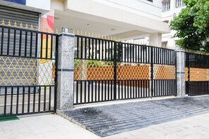 A gated entrance with a marble pillar, a metal gate with decorative spikes, and a wooden fence.