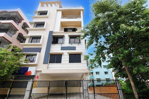 A multi-story residential building with balconies, a gated entrance, and a clear sky.