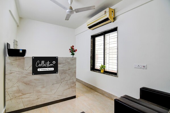 A reception desk with a sign, a ceiling fan, an air conditioning unit, a window with a view, and a power outlet.