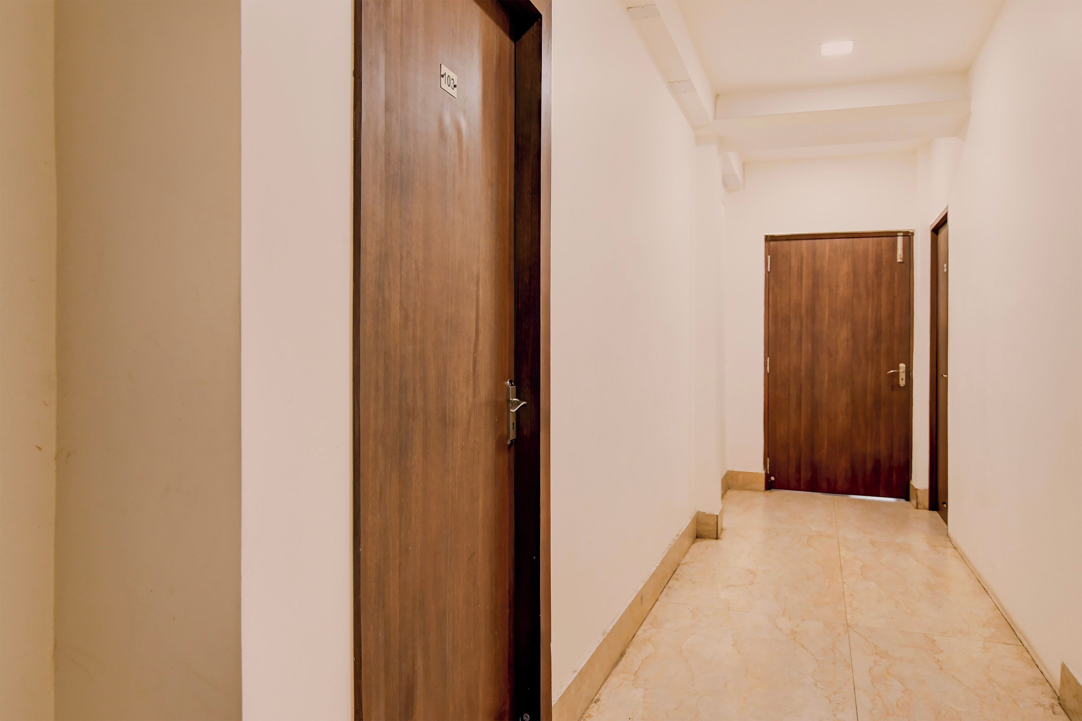 A corridor with wooden doors and a tiled floor.