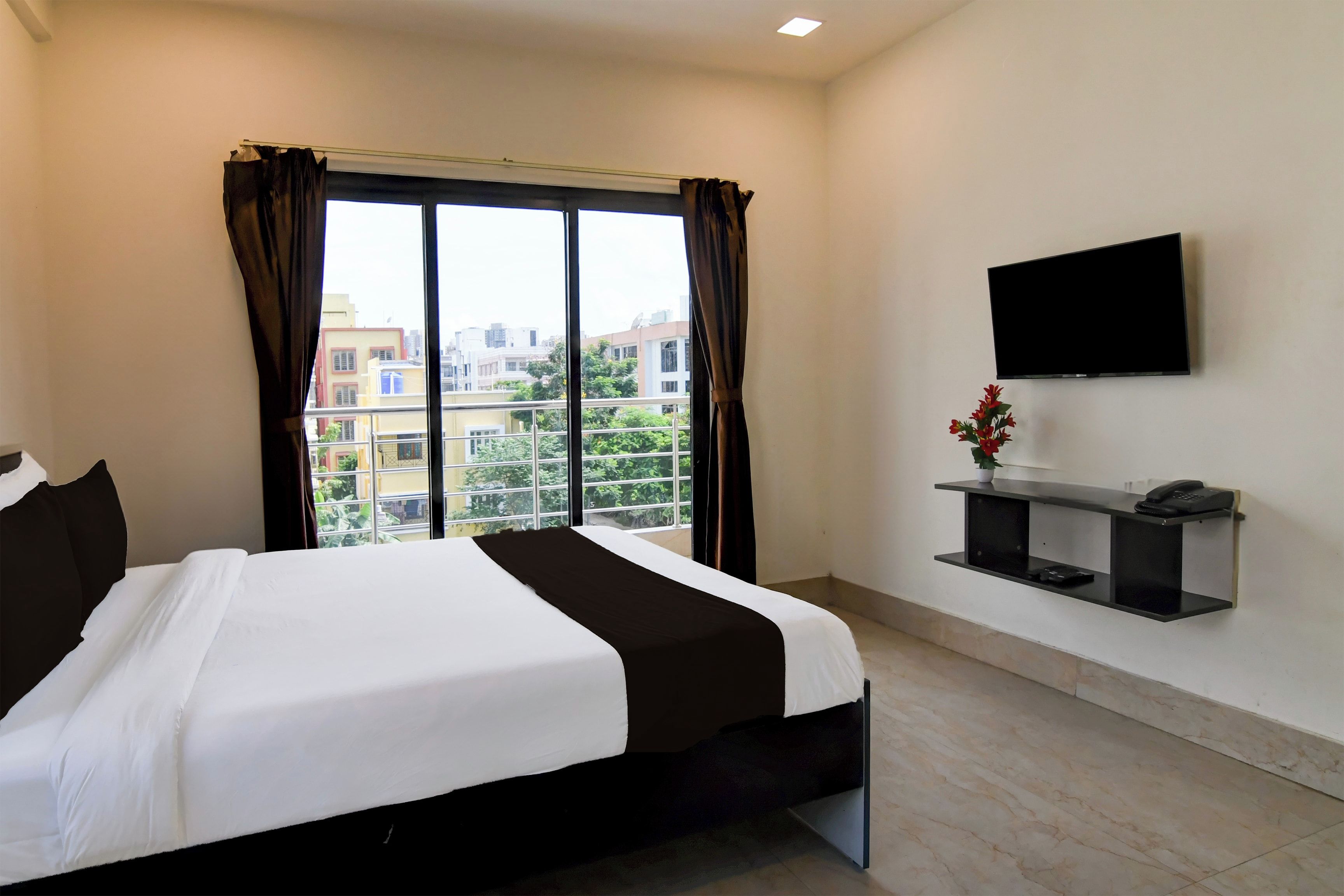 Habitación de hotel con una cama grande, un televisor de pantalla plana en la pared y vistas a la ciudad por la ventana.