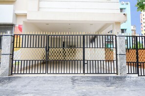 A gated entrance to a building with a covered driveway and a visible staircase leading to the entrance.