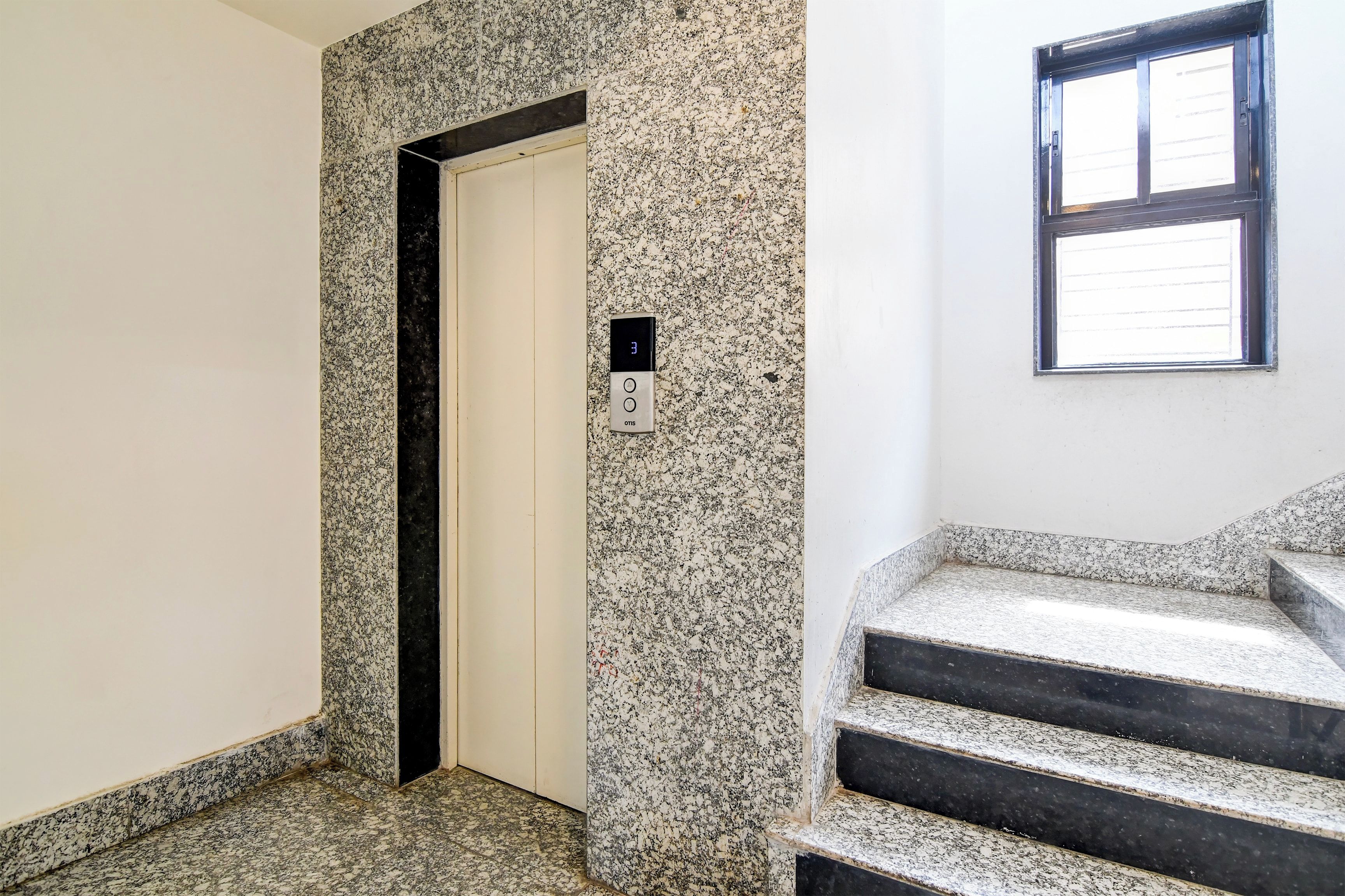 A hallway with a door, a stairwell, and a window.