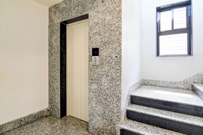 A hallway with a door, a stairwell, and a window.
