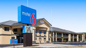A motel with a prominent '6' sign, a clear entrance, and a signboard advertising wireless and HBO services.