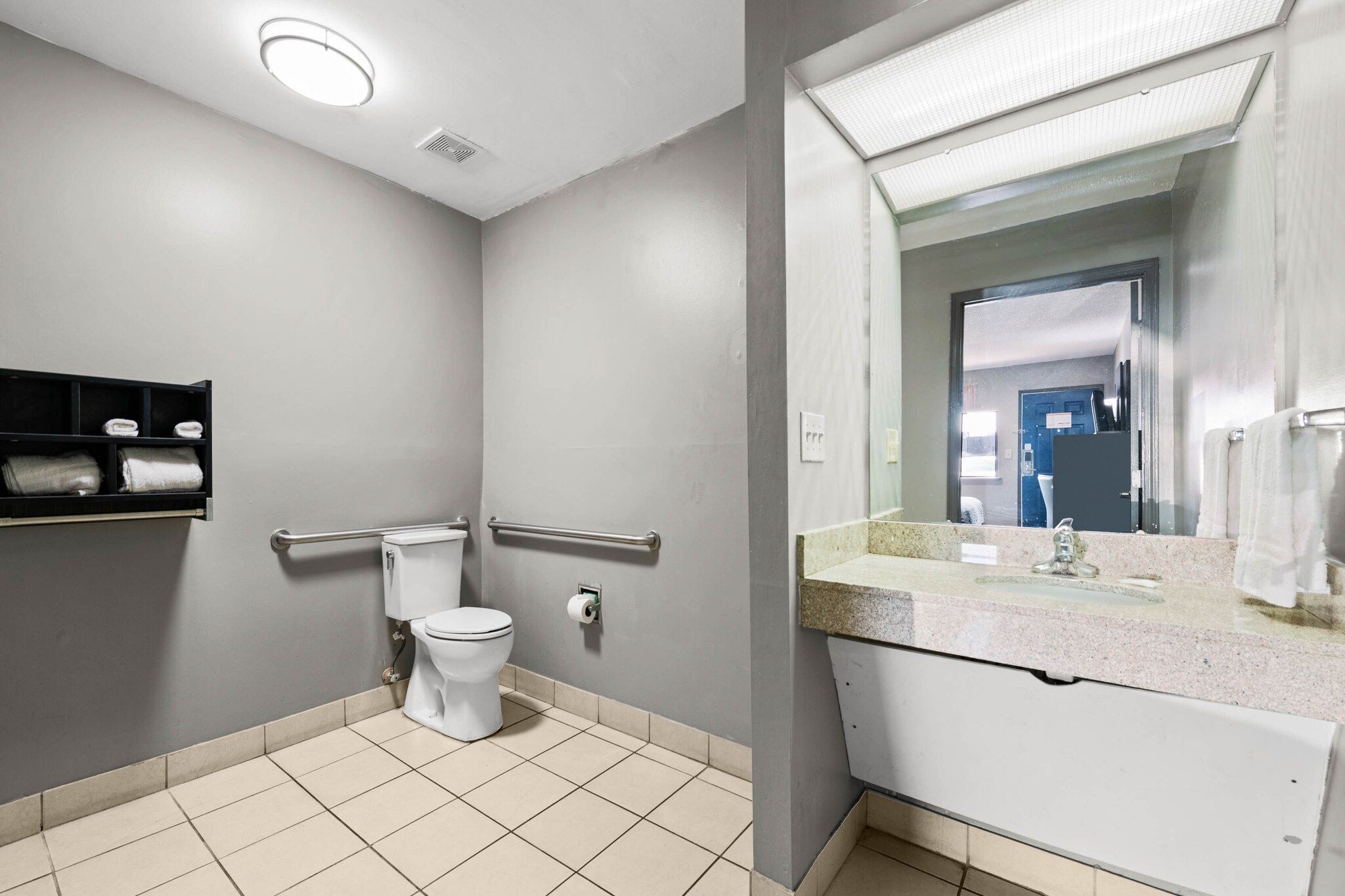 A modern bathroom with a toilet, hand dryer, and a sink with a mirror.