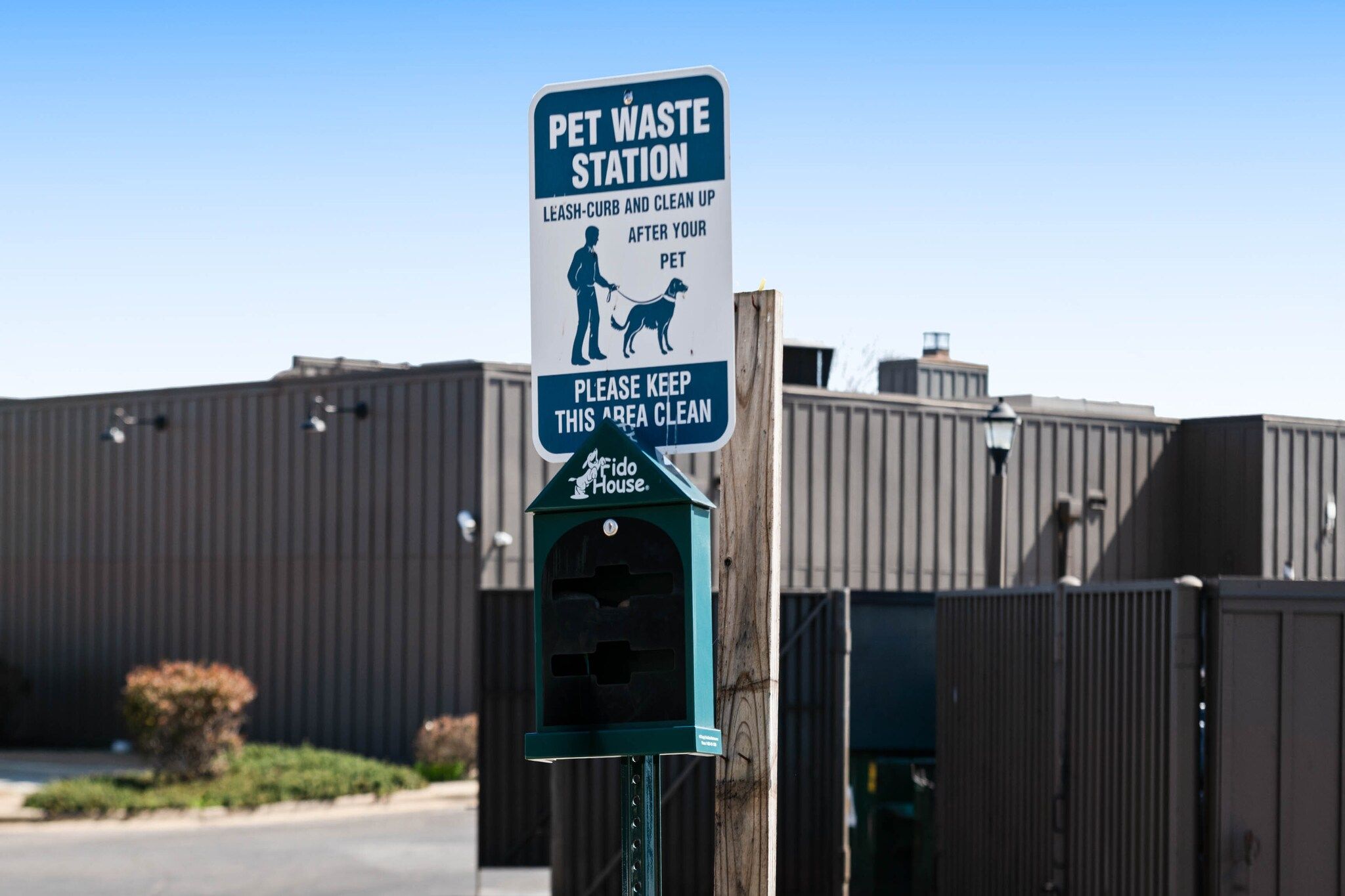 Schild für eine Tierkotstation mit Mülleimer und dem Fido House Logo.
