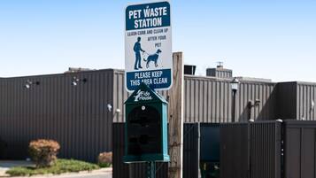 Schild für eine Tierkotstation mit Mülleimer und dem Fido House Logo.