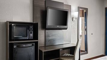 Une chambre d’hôtel équipée d’un téléviseur à écran plat fixé au mur, d’un mini-réfrigérateur, d’un four à micro-ondes et d’une chaise.