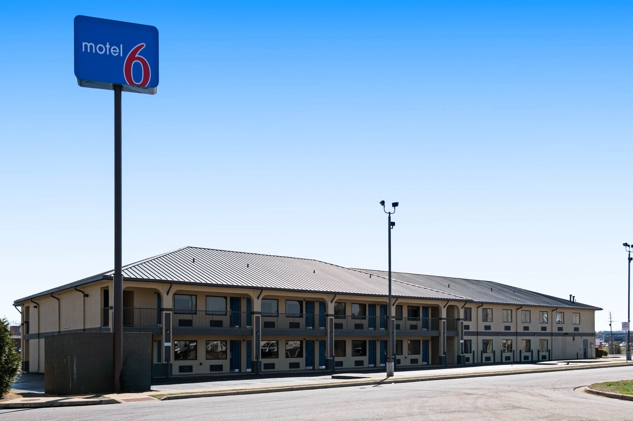 Ein Motel mit einem großen, eingeschossigen Gebäude, zahlreichen Fenstern und einem gut sichtbaren Schild, das anzeigt, dass es sich um Motel Nummer 6 handelt.