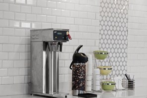 A coffee machine with a digital display, a coffee grinder, and a set of coffee cups and saucers.