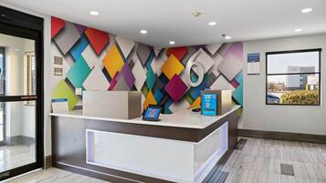 A reception desk with a modern design, a digital screen, and a sign offering membership rates.