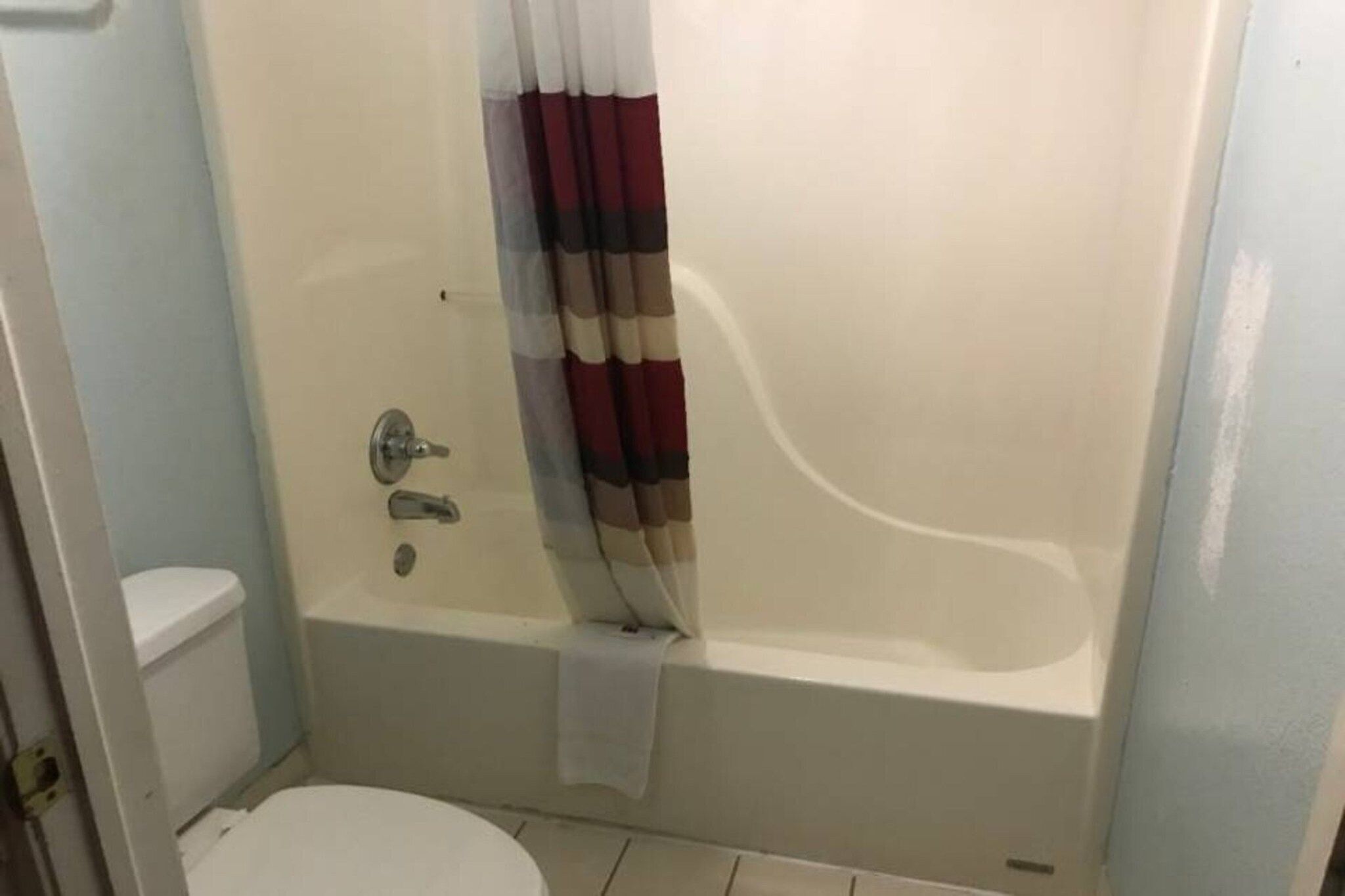 A bathroom with a bathtub, toilet, and a shower curtain.