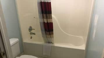 A bathroom with a bathtub, toilet, and a shower curtain.