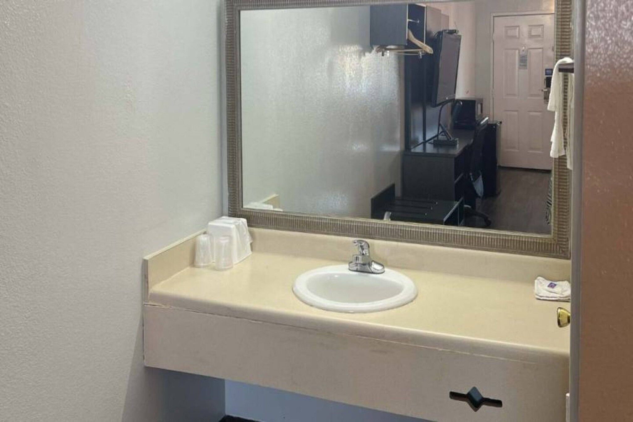 Et badeværelse med håndvask, spejl og toiletartikler.