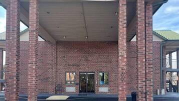 A building with a brick facade, a covered entrance, and a set of stairs leading up to the entrance.