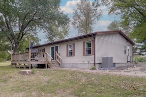 A single-story house with a front porch, a small deck, and a large air conditioning unit.