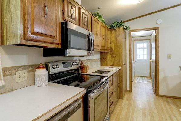 A kitchen with wooden cabinets, a microwave, stove, and a dishwasher.