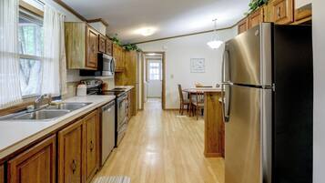 Una cocina con armarios de madera, electrodomésticos de acero inoxidable y una zona de comedor con mesa y sillas.