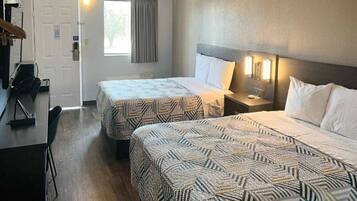 A hotel room with two beds, a desk, and a chair.