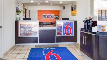 A motel reception desk with a welcome mat and a large number 6 sign.
