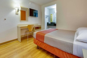 A hotel room with a bed, a desk, a chair, a television, and a bathroom mirror. - 1 Queen Bed | Tempe, AZ (Tempe)