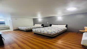A room with two beds, a wooden floor, and a white door.