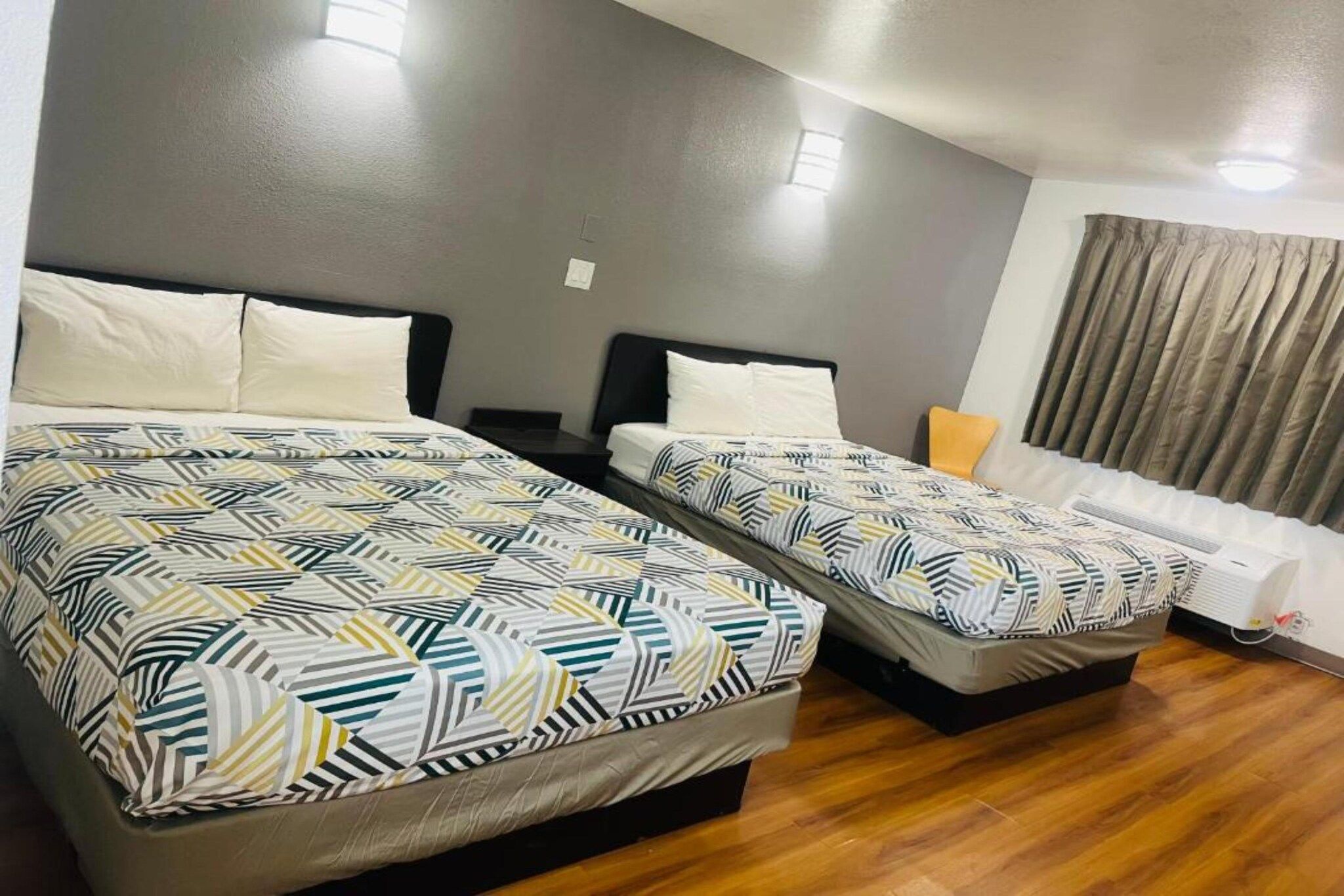 Habitación de hotel con dos camas, un sofá y una ventana con cortinas.
