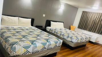 Habitación de hotel con dos camas, un sofá y una ventana con cortinas.