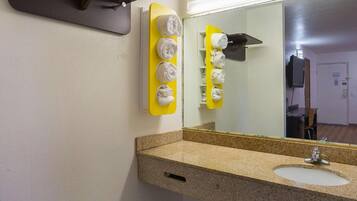 A bathroom with a granite countertop, a sink, and a mirror.