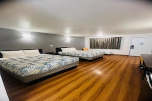 Habitación de hotel con dos camas, piso de madera, un escritorio y una silla.