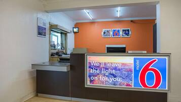 A hotel reception desk with a large sign reading 'We leave the light on for you.'