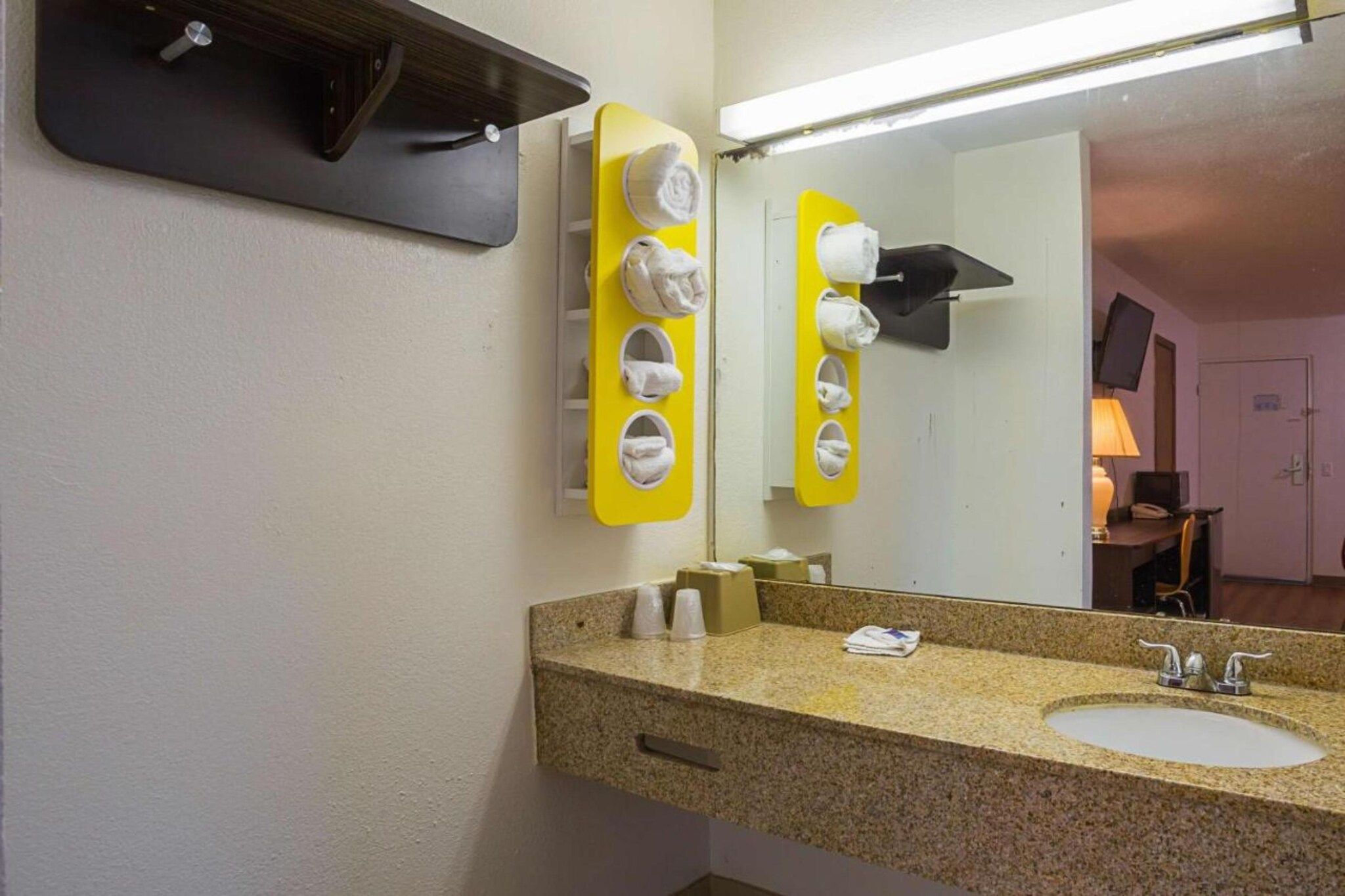 A bathroom with two sinks, a mirror, and a towel rack with multiple towels.
