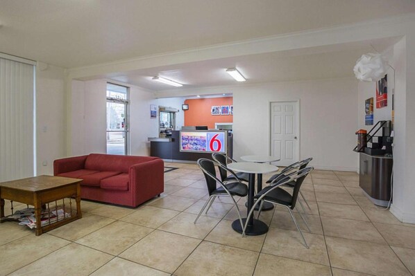 A living room with a red sofa, a coffee table, and a dining area with a table and chairs.
