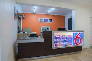 A hotel reception desk with a large sign stating 'We'll leave the light on for you.'