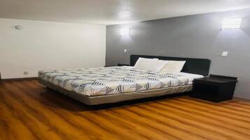 Een slaapkamer met een bed, een nachtkastje en een wandlamp.